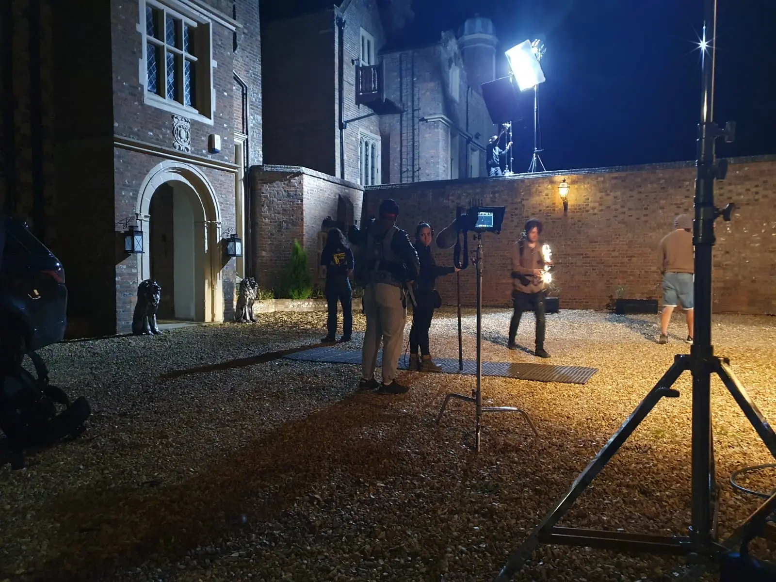 Lighting stands and crew in the courtyard after dark