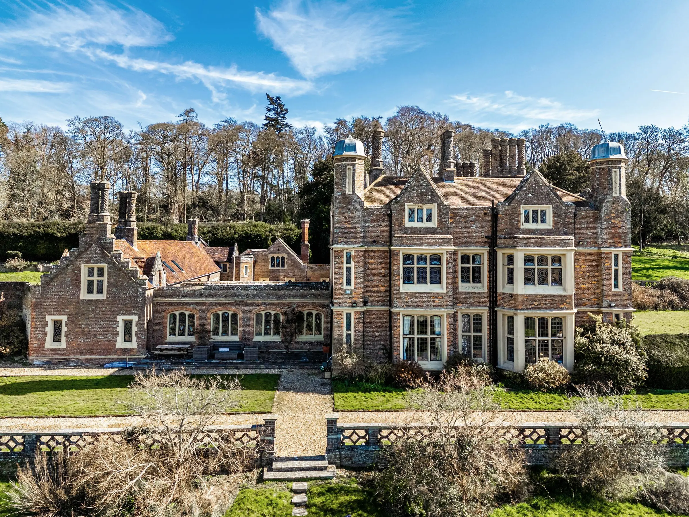 The garden front of Markyate Manor seen from the terrace steps: red brick, stone bay windows, tall chimney stacks and domed turrets