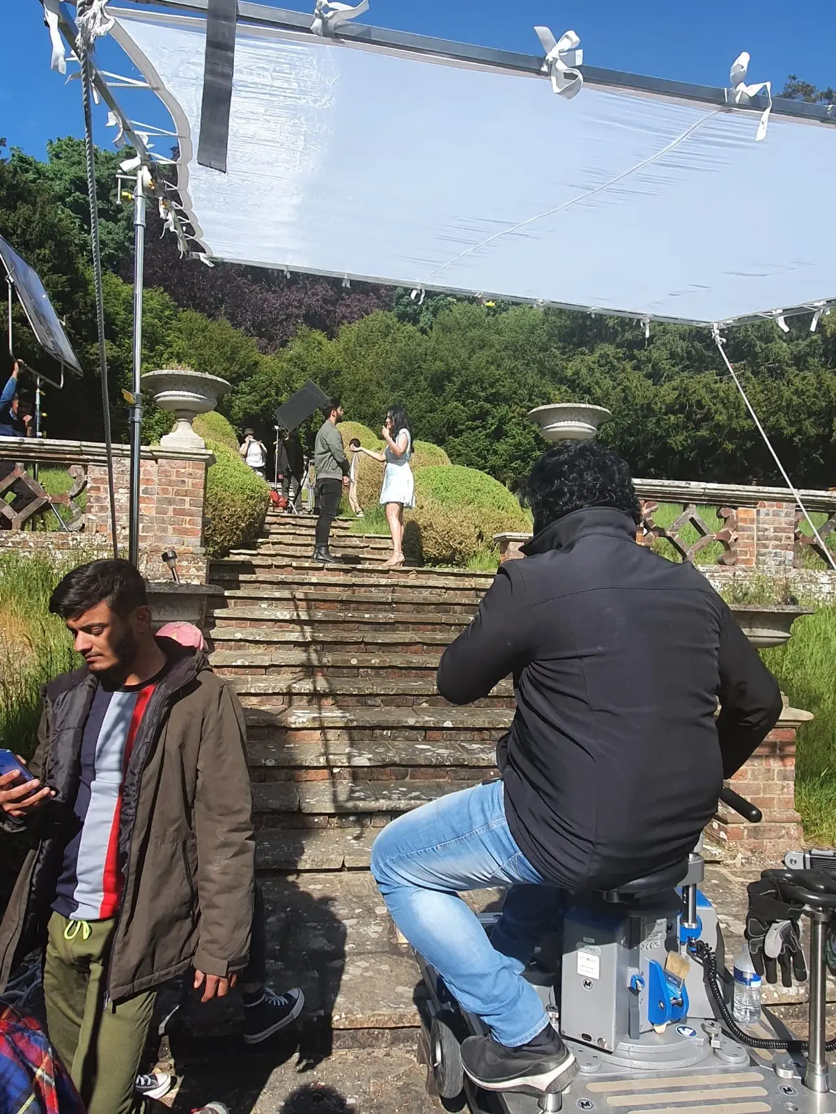 A camera dolly at the foot of the garden steps under a large overhead diffusion frame