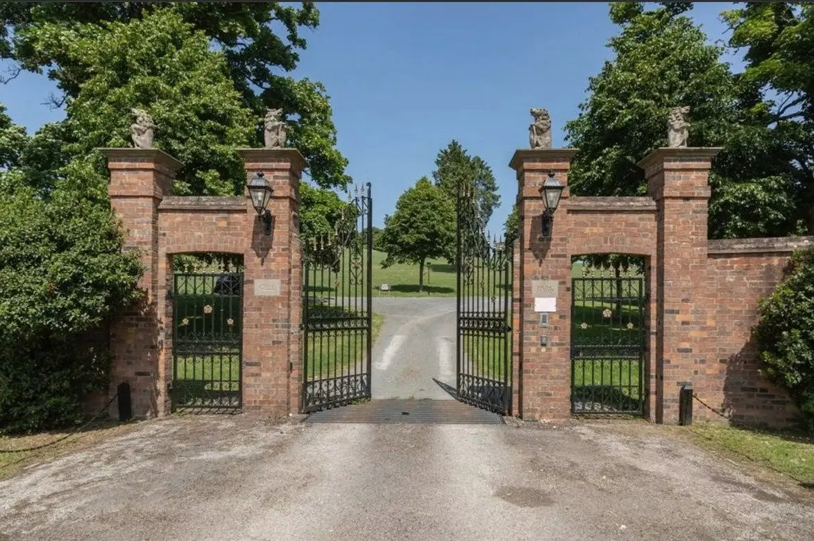 The main gates: brick piers topped with carved stone beasts, and iron gates opening onto the drive