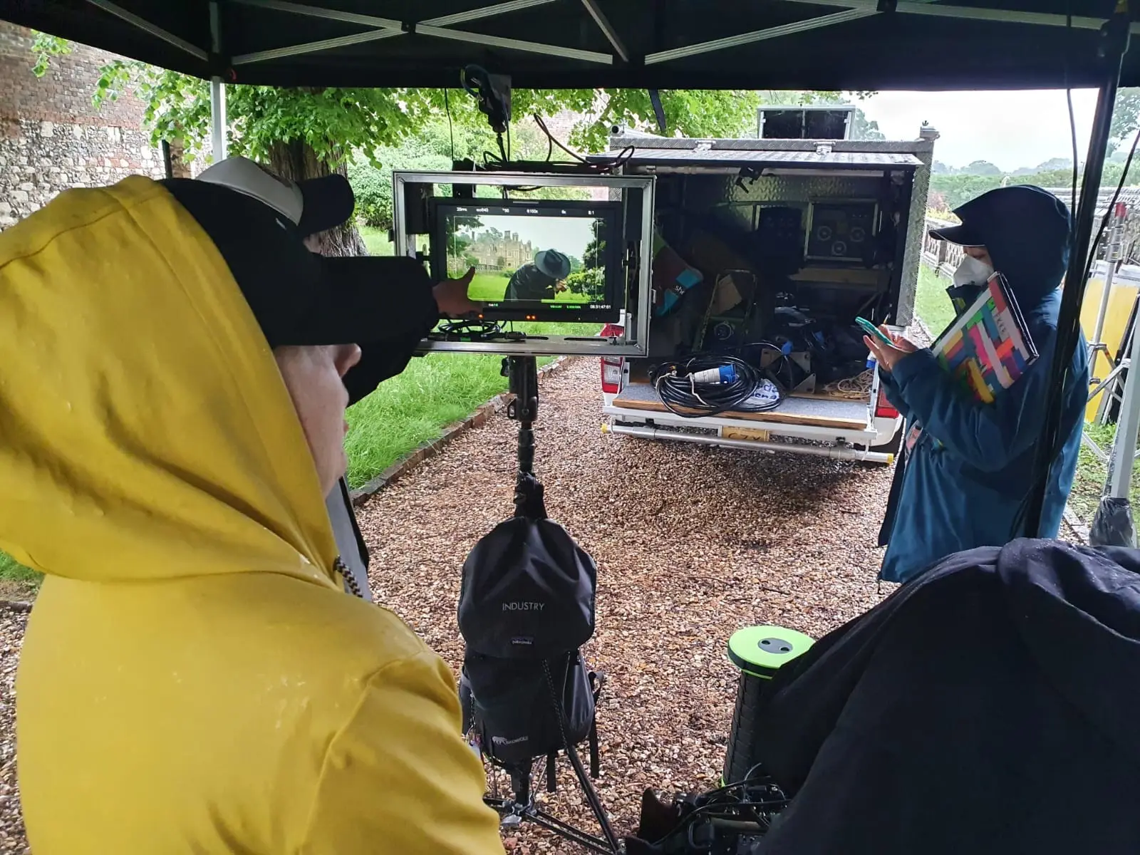 Crew watching monitors under a gazebo beside a camera truck
